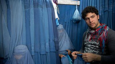 Nazar, right, a salesman at a burqa store, helps women to choose a burqa.