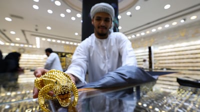 An exhibitor shows a gold ornament to a customer at a jewellery shop inside the gold market in Dubai. The IMF expects the UAE economy to grow 4 per cent this year despite tariff uncertainty. EPA