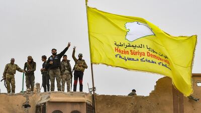 Syrian Democratic Forces fighters flash the victory sign next to their flag atop a roof in the village of Baghouz on March 24, 2019, a day after declaring the ISIS "caliphate" defeated. AFP