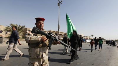An Iraqi soldier stands guard as Shiite pilgrims walk to the holy city of Kadhimiya during a religious ritual commemorating the anniversary of Imam Mohammed Al Jawad's death. Saad Shalash / Reuters