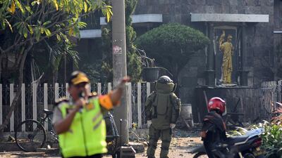 A member of the police bomb squad unit examines the site of an explosion outside the Immaculate Santa Maria Catholic Church, in Surabaya, East Java, Indonesia. Reuters