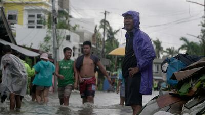 Residents wade from floodwaters in a flooded village in Sorsogon province. AP