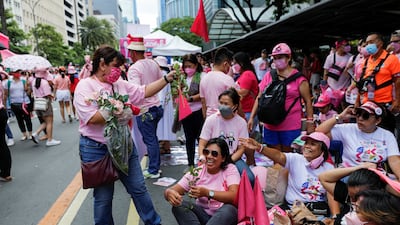 Supporters of Leni Robredo distribute flowers to women at a campaign rally. Reuters