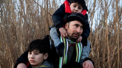 A man holds his three sons as migrants from Afghanistan arrive on a dinghy on a beach near the village of Skala Sikamias, after crossing part of the Aegean Sea from Turkey to the island of Lesbos, Greece, March 2, 2020. REUTERS/Alkis Konstantinidis TPX IMAGES OF THE DAY