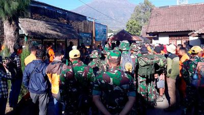 Rescue teams gather to start extracting the trapped tourists from Indonesia's Mount Rinjani, seen in the background, on July 30, 2018. AP