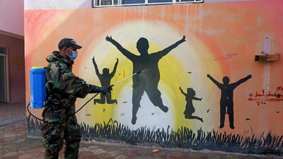 A member of the civil defence team disinfects a mural to prevent the spread of the coronavirus at a school, in Najaf. Reuters