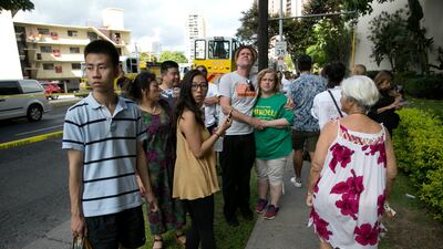 Onlookers stand on a sidewalk as a fire burns at the Marco Polo apartment complex in Honolulu. Marco Garcia / AP Photo