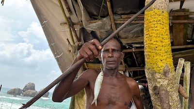Seena Th, 60, a third-generation stilt fisherman, showing a sardine he caught