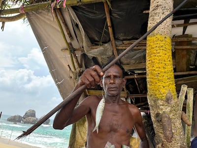 Seena Th, 60, a third-generation stilt fisherman, shows a sardine hooked to a fishing rod. Taniya Dutta / The National