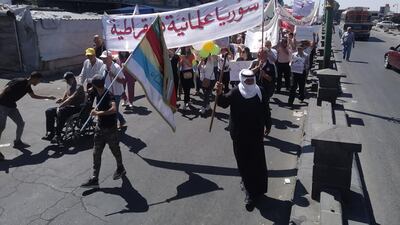 Demonstrators march in the southern Syrian city of Suweida, on August 16, 2022, with a banner that reads "Syria secular and democratic", at the one year anniversary celebration of the protest movement against President Bashar Al Assad, in the mostly Druze province. Photo: Suhail Thubian.