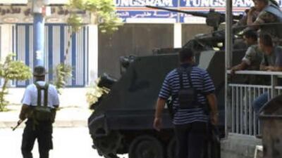Gunmen walk past Lebanese soldiers on armoured personnel carriers in the Bab Tibbaneh district area during clashes between supporters of the government and Alawite gunmen close to the Hizbollah-led opposition in Tripoli.