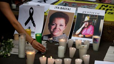 A woman places a candle in front of pictures of murdered journalists Miroslava Breach, left, and Javier Valdez during a demonstration against the killing of journalists, outside the Interior Ministry in Mexico City. More than three dozen Mexican media organizations announced Monday, Dec. 4, 2017 that they are joining forces to try to combat a wave of journalist killings in the country, including at least nine this year. Rebecca Blackwell / AP