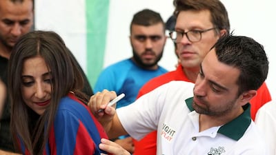 Former Barcelona football player Xavi Hernández, who now plays for Al-Sadd in the Qatar Stars League, signs a Barcelona shirt as he visits the Al Baqaa Palestinian refugee camp near Amman, Jordan, on September 29, 2016. Khalil Mazraawi / Agence France-Presse