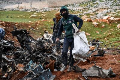 Syrians gather around the wreckage of a government military helicopter that was shot down Friday, in the countryside outside Idlib, Syria, Saturday, February 15, 2020. AP