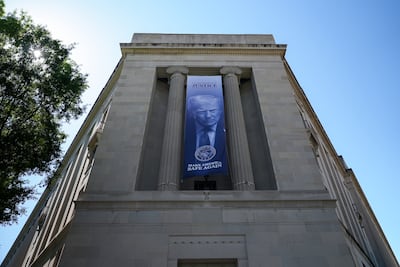 Outside the US Justice Department, a banner with President Donald Trump's face looms over Washington. Joshua Longmore / The National