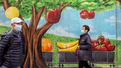 Pedestrians wearing protective masks walk past a mural featuring fruits in Hong Kong, China. Bloomberg