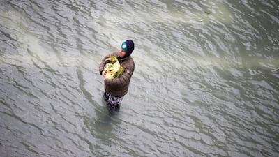 A man holds his bag as he stands in a flooded St. Mark's Square in Venice, Italy, Friday, Nov. 15, 2019. The high-water mark hit 187 centimeters (74 inches) late Tuesday, Nov. 12, 2019, meaning more than 85% of the city was flooded. The highest level ever recorded was 194 centimeters (76 inches) during infamous flooding in 1966. AP Photo