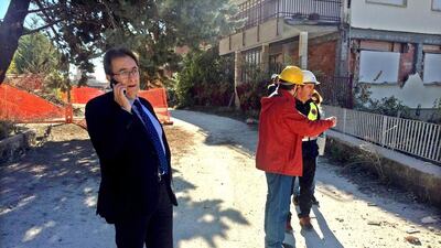 Massimo Cialente, the L’Aquila mayor, left, speaks on his mobile as he checks the damage in his town. Alberto Orsini / EPA