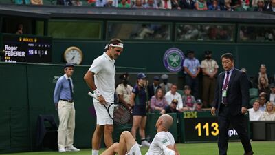 Roger Federer speaks to Adrian Mannarino after he slipped on the grass and picked up a match-ending injury. AFP