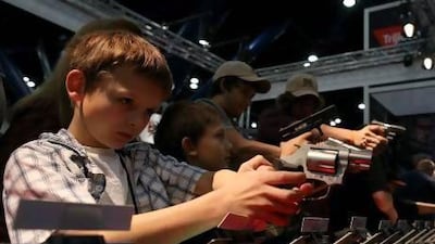 A boy inspects a handgun during the 2013 NRA annual meeting in Houston, Texas.