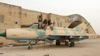 Members of Al-Qaeda's Syrian affiliate and its allies sit on top of a former Syrian army MiG-21 figther jet after they seized the Abu Duhur military airport. AFP