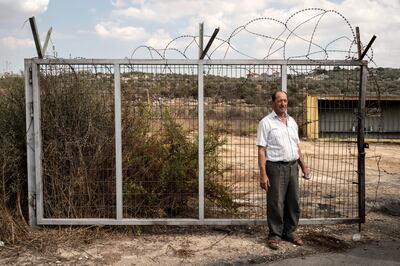 Palestinian farmer Ibrahim Amar, 64, stands by a wall that separates him from his olive groves in Qaffin, occupied West Bank. Tanya Habjouqa / Noor for The National