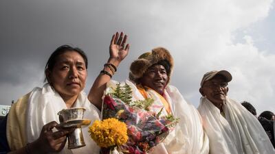 Kami Rita Sherpa waves as he stands between his wife and father. Narendra Shrestha / EPA