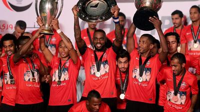 Al Ahli players lift the Arabian Gulf League trophy, centre, following their final match of the season on Sunday. They also display their League Cup trophy, right, and their Super Cup trophy, left. Ahli finished off their domestic season by beating Al Dahfra 5-1 in Dubai. Satish Kumar / The National / May 11, 2014