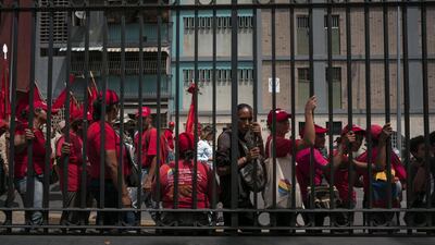 Pro-government supporters stand behind a fence during a rally outside of Miraflores Palace in Caracas, Venezuela. Bloomberg