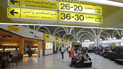 Passengers wearing protective masks wait for flights at the departure hall of Baghdad international airport. AFP
