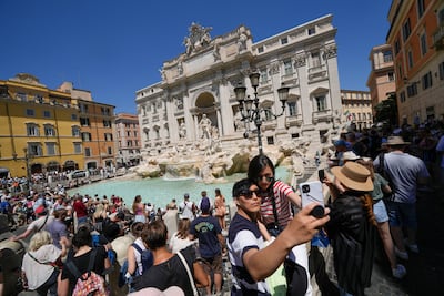 Tourists take a selfie in front of the Trevi Fountain, in Rome. AP