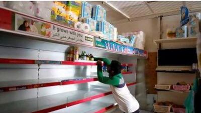 A staff member at the Corniche Al Madina grocery in Al Nahda, Sharjah, clears the shelves of perishable goods as the building in which it operates has been without electricity for six days.