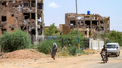 A woman walks past damaged buildings in the Lamab suburb of Sudan's capital Khartoum. AFP