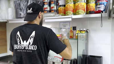 El Hakim creates one of their most popular dishes: a pulled beef chuck burrito. Chris Whiteoak / The National