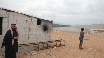 Syrian Abu Jaber stands next to a ladder which he created to climb over the Turkish border wall at an informal camp in Kafr Lusin village in Syria's northwestern province of Idlib. AFP