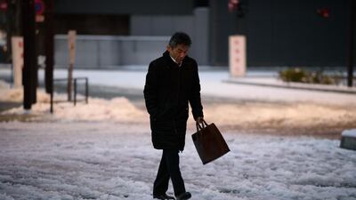 A morning commuter walks across a snow-covered street in Tokyo, Japan, on Tuesday. Akio Kon / Bloomberg