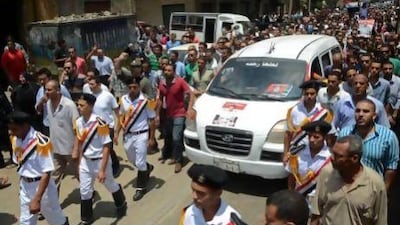 Egyptian policemen march with a vehicle carrying the body of a comrade, killed in Cairo on Monday in clashes outside the Republican Guard headquarters that killed more than 50 people.