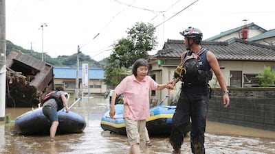 A stranded woman is rescued following a heavy rain in Hitoyoshi, Kumamoto prefecture, southern Japan. Kyodo News via AP