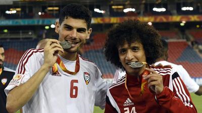 Mohaned Salem, left and Omar Abdulrahman bite down on their medals.