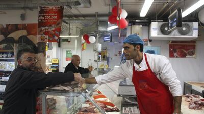 Syrian refugee Mansour Mafalani serves a customer at a Carrefour supermarket in Amman on October 31, 2017. Mafalani is one of 34,000 Syrian refugees granted work permits by Jordan this year. Taylor Luck for The National