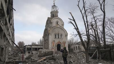 A Ukrainian serviceman taking a photograph of a church in a residential district after shelling in Mariupol. Photo: Evgeniy Maloletka / Associated Press