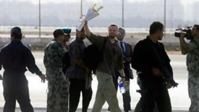 A European tourist, who was taken hostage by bandits in the Egyptian desert 10 days ago and rescued today by the Egyptian army, waves a bunch of flowers as he is escorted across the tarmac of the Army's east Cairo base.