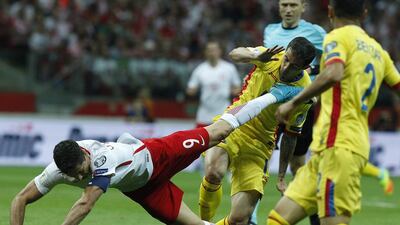 Poland’s Robert Lewandowski, left, falls over vieing for the ball with Romania’s Bogdan Stancu during their World Cup qualifer in Warsaw. Czarek Sokolowski / AP Photo
