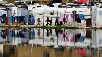 Children play outside as their tents are reflected in a pool of rain water at a refugee camp, in Bar Elias, Lebanon. AP Photo