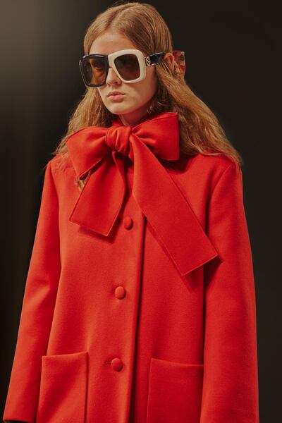 A heavy coat is given a playful bow at the neck, while mismatched sunglasses make this pure Gucci