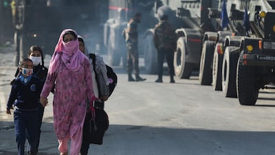 Women and schoolchildren walk past Indian soldiers on the outskirts of Srinagar, Kashmir. AFP