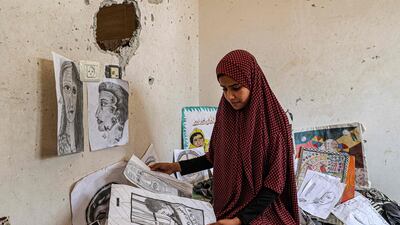 The sister of Palestinian artist Diana al-Amour, 22, who was reportedly killed in an Israeli bombardment days before, looks through her sketches in her room at the family home near the border with Israel, east of Khan Yunis in the southern Gaza Strip. AFP