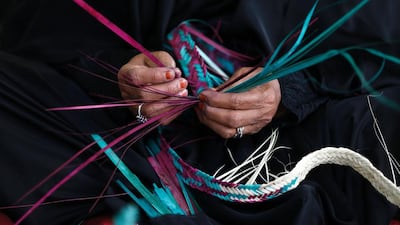 An Emirati woman weaves palm fronds.