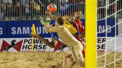 Brazil's Bruno da Silva Xavier, centre, takes a shot against Russia's goalkeeper Andrey Bukhlitskiy during their quarterfinal Beach Soccer Intercontinental Cup match at the Dubai International Marine Club in Dubai on Thursday. Christopher Pike / The National