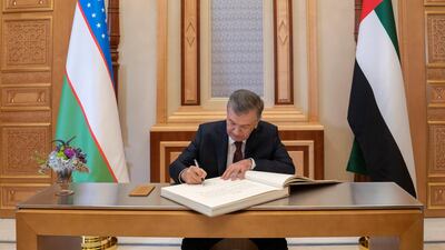 Mr Mirziyoyev signs the visitors book during a reception at the Presidential Palace.
